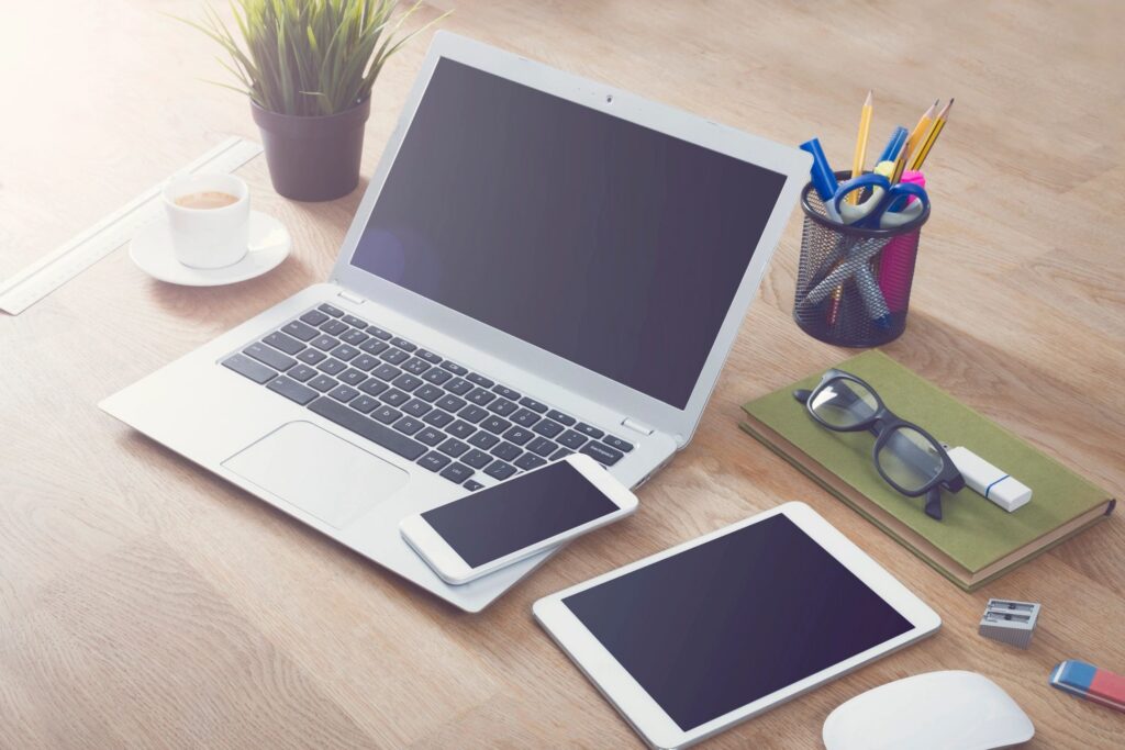 laptop, cell phone, and tablet on table.